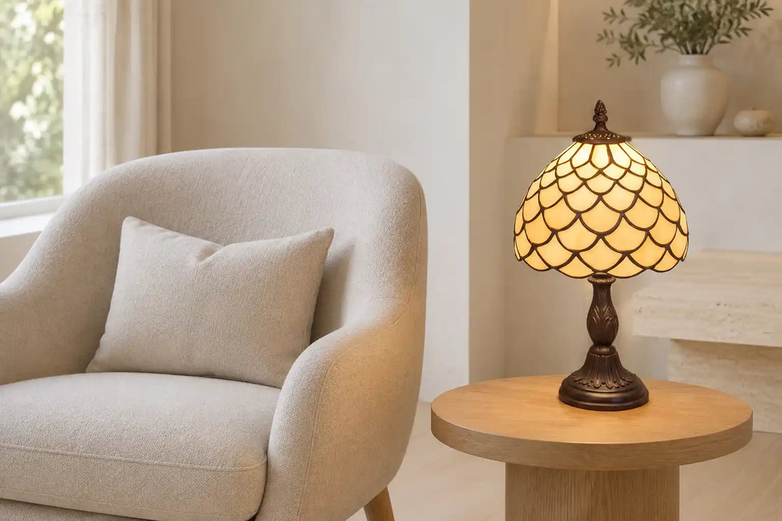 Brandende Tiffany tafellamp 7006 met geschubd crème-amber glaspatroon op een houten bijzettafel naast een lichte fauteuil | RORUVERA