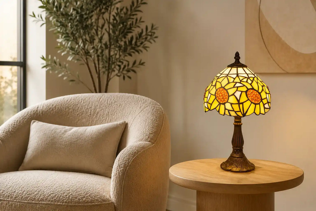 Brandende Tiffany tafellamp 7007 met geel-oranje zonnebloemmotief op een lichte bijzettafel naast een bouclé fauteuil in een moderne woonkamer | RORUVERA