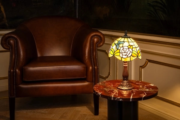 7013 - Tiffany tafellamp met rozenmotief op een marmeren bijzettafel naast een leren fauteuil | RORUVERA
