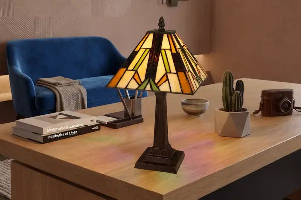 Tiffany tafellamp Art. 7014 brandend op een lichte houten tafel in een modern interieur met een blauwe bank | RORUVERA