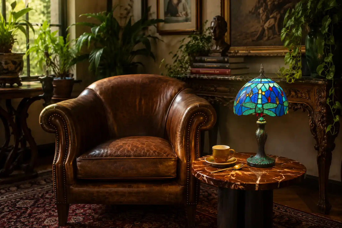 Tiffany tafellamp met blauw-groen libellemotief in artistiek klassiek interieur met leren fauteuil, kunst, boeken en groene planten | RORUVERA