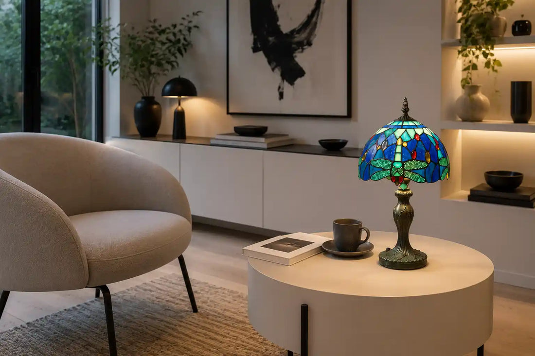 Tiffany tafellamp met blauw-groen libellemotief op moderne lichte bijzettafel naast crèmekleurige fauteuil in een strak en licht interieur | RORUVERA