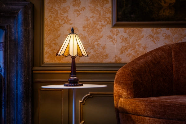 7019 - Tiffany tafellamp met crèmekleurige glazen kap op een ronde witte bijzettafel naast een fauteuil | RORUVERA