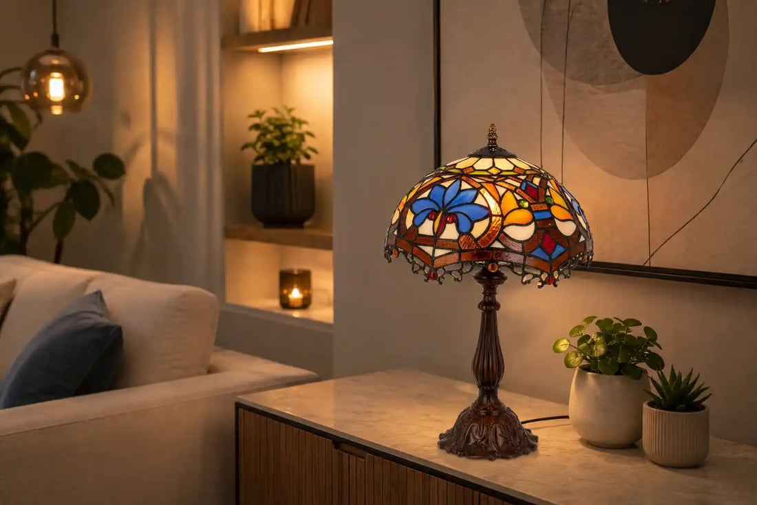 Kleurrijke Tiffany tafellamp met bloemmotief in blauw, amber en rood op een modern dressoir in een warme woonkamer met abstracte wandkunst en kleine groene planten | RORUVERA