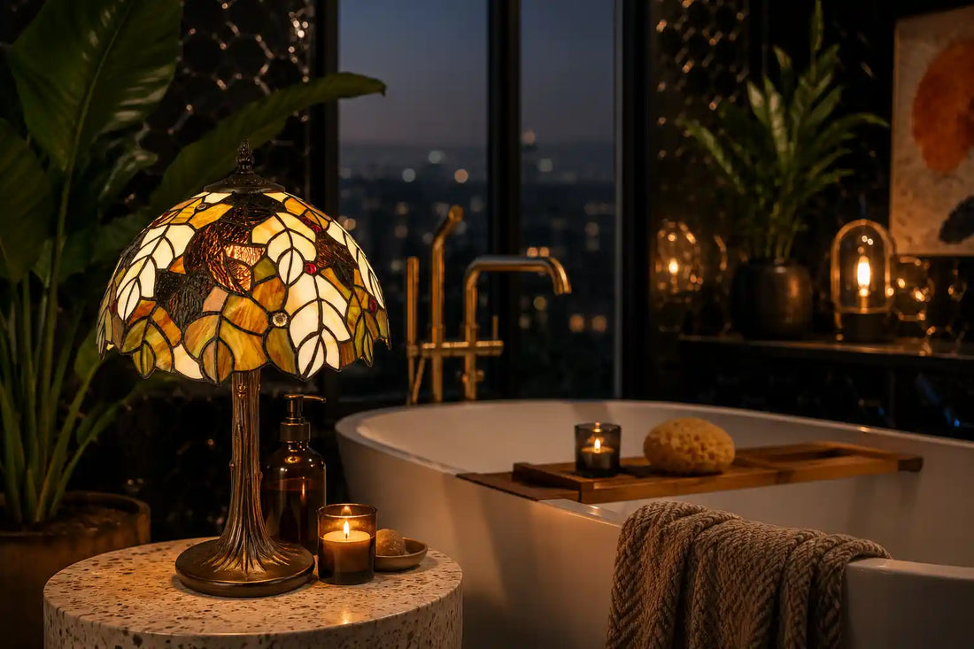 Tiffany tafellamp met bladmotief in crème, amber, groen en bruin glas-in-lood in een luxe donkere badkamer, naast een vrijstaand bad en omringd door groene planten en warme sfeerverlichting | RORUVERA
