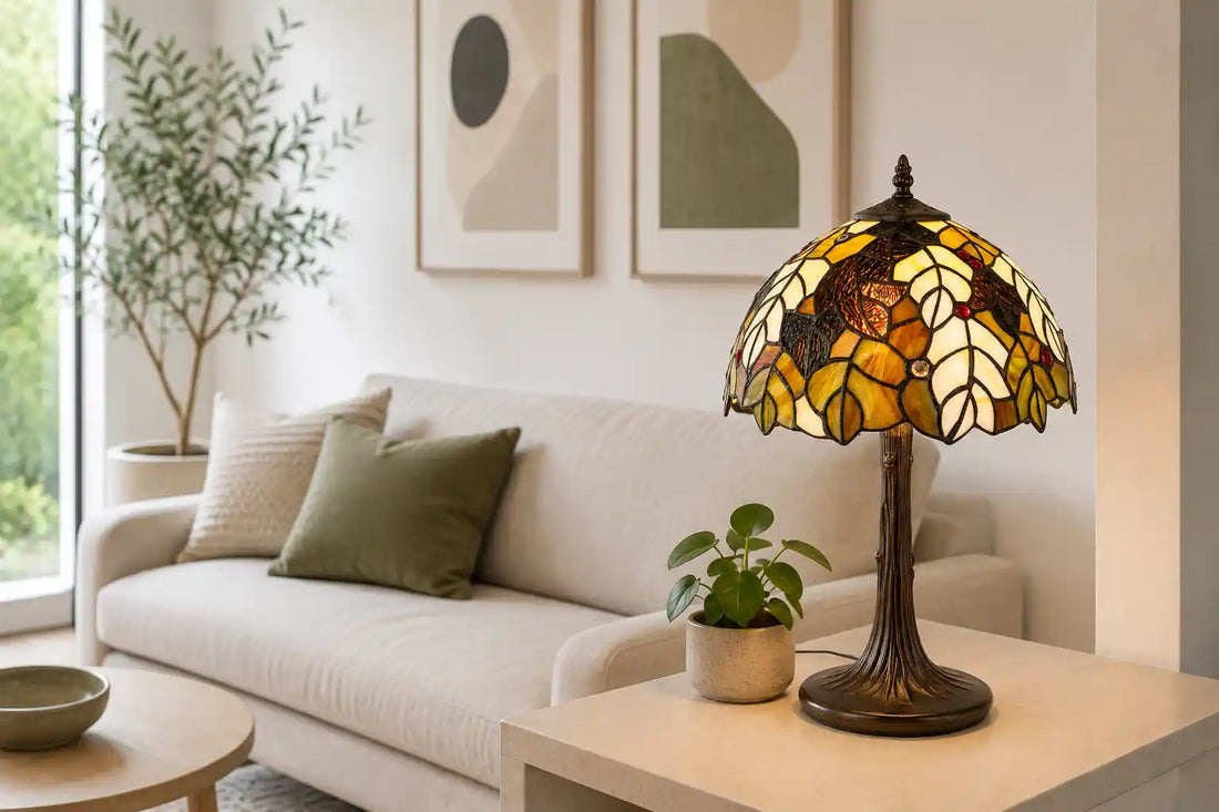 Tiffany tafellamp met natuurlijk bladmotief in crème, amber, groen en bruin glas-in-lood op een lichte sidetable in een moderne woonkamer met neutrale meubels, abstracte kunst en groene planten | RORUVERA