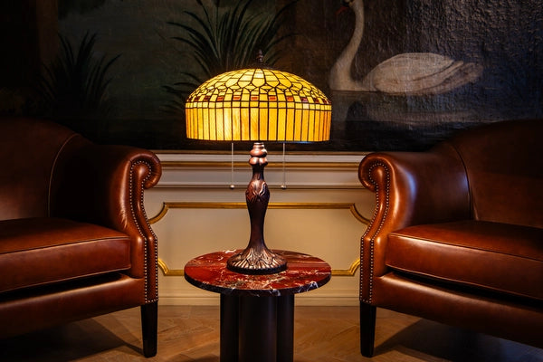 7034 - Tiffany tafellamp met amberkleurige geometrische kap op een marmeren tafeltje tussen twee leren fauteuils | RORUVERA