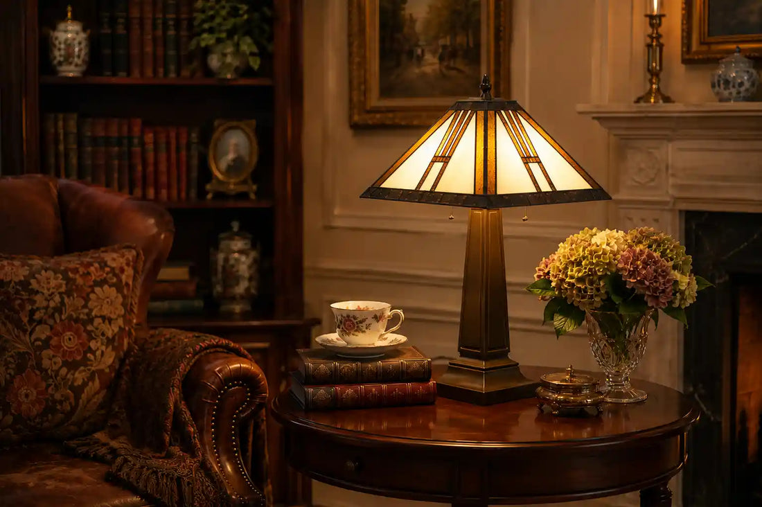 Tiffany tafellamp met geometrische crème en amberkleurige kap op klassieke houten tafel tussen boeken, bloemen en leren fauteuil | RORUVERA