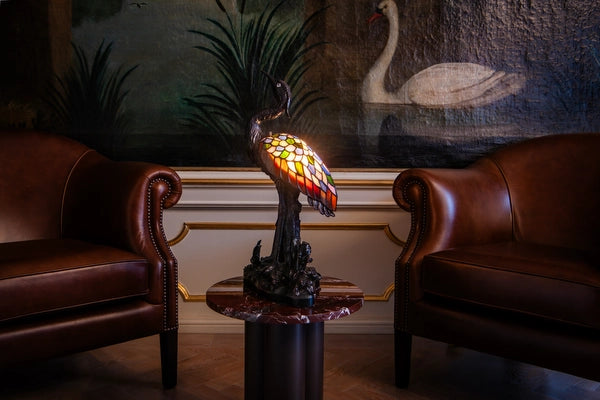 7060 - Tiffany reigerlamp op een ronde zuiltafel naast een cognacleren bank in een klassiek ingericht interieur | RORUVERA