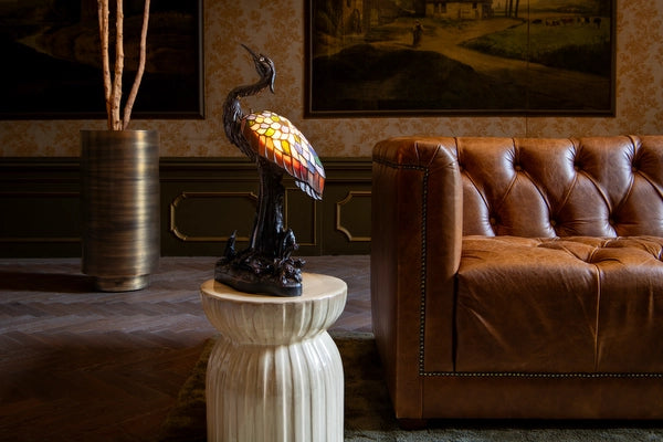 7060 - Tiffany reigerlamp op een marmeren bijzettafel tussen twee leren fauteuils in een klassiek interieur | RORUVERA