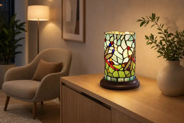 Brandende Tiffany tafellamp 7176 met kleurrijk libellenmotief op een lichte houten kast in een rustige, moderne woonkamer | RORUVERA