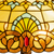 Detail Tiffany vloerlamp art nouveau met sierpatroon van glas in lood in geel-, groen- en ambertinten