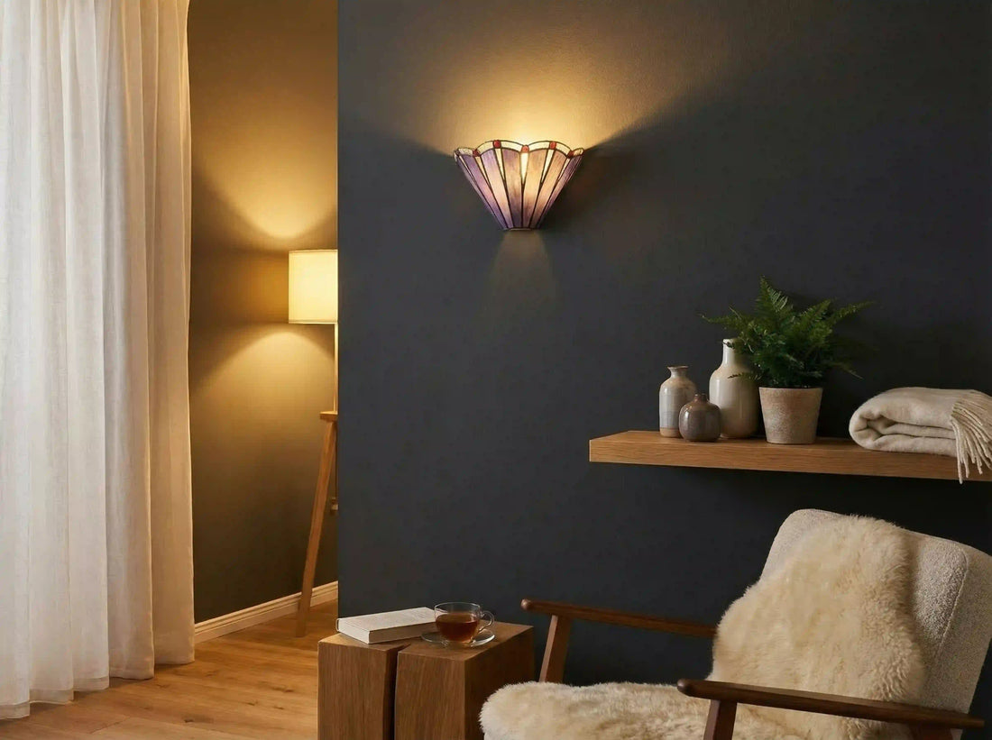 Tiffany wandlamp met paars glas aan een donkere wand boven een sfeervolle leeshoek met houten fauteuil | RORUVERA