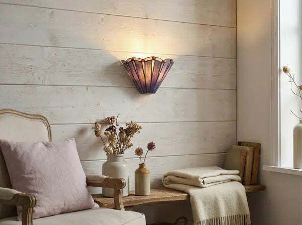 Tiffany wandlamp met paars glas aan een lichte h outen wand boven een bankje met decoratieve accessoires | RORUVERA