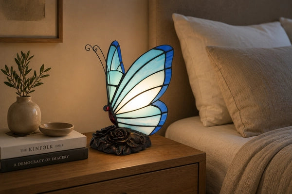 8001 - Blauwe Tiffany vlinderlamp op een houten nachtkastje naast een bed met neutraal beddengoed | RORUVERA