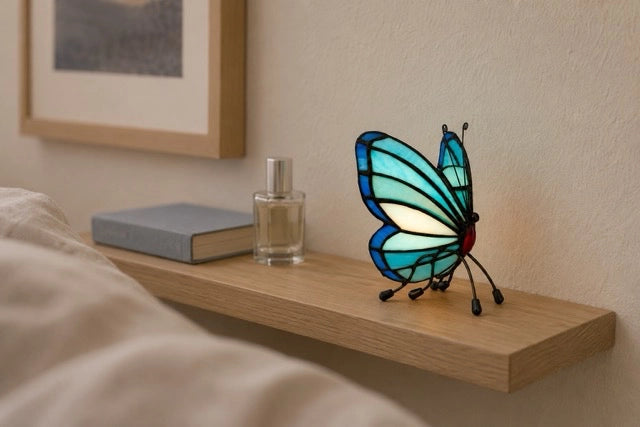 Blauwe Tiffany vlinder waxinelichthouder op een houten wandplank met boek en parfumflesje