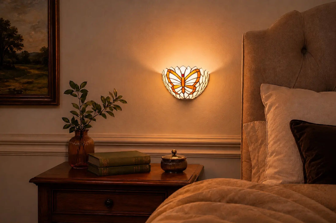 Tiffany wandlamp met vlindermotief boven een houten nachtkastje naast een gestoffeerd bed in een sfeervolle slaapkamer | RORUVERA