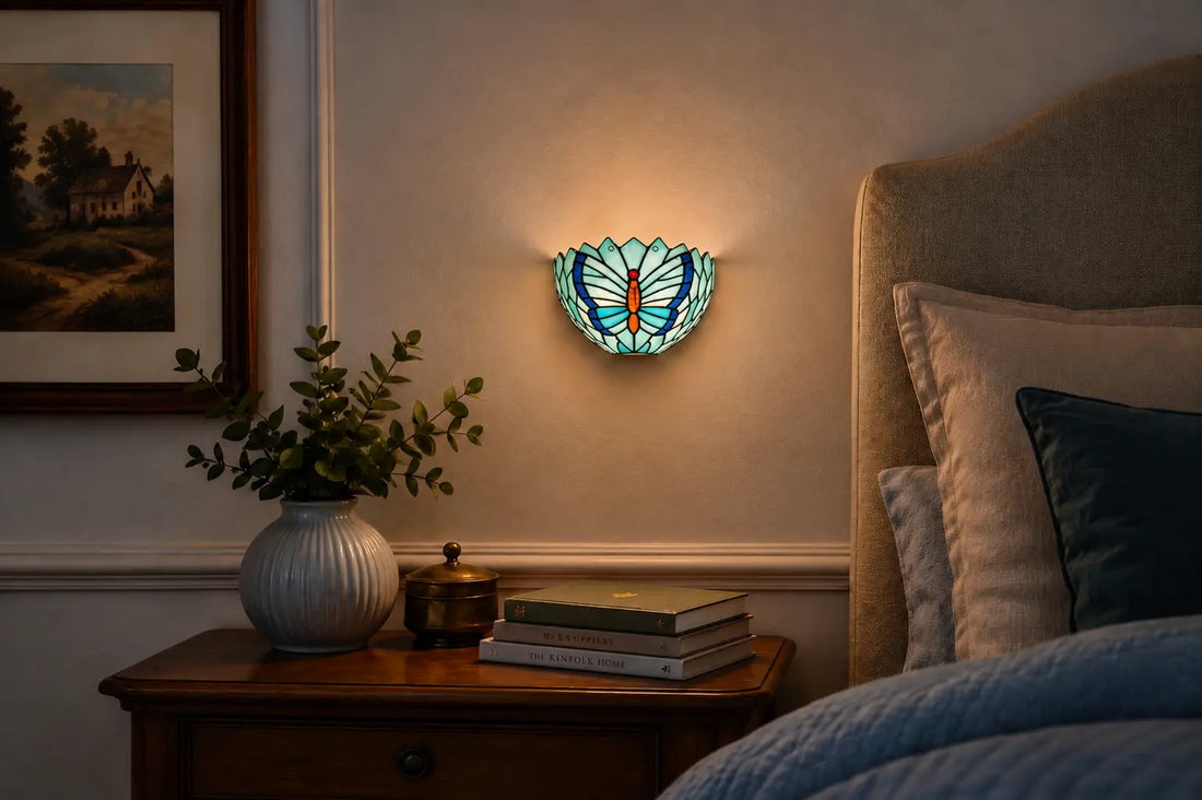 Tiffany wandlamp met blauw vlindermotief boven een houten nachtkastje naast een comfortabel bed in een sfeervolle slaapkamer | RORUVERA